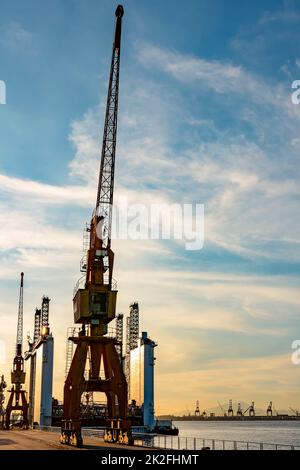 Mehrere Kräne und der Blick auf den Pier in der Dämmerung Stockfoto