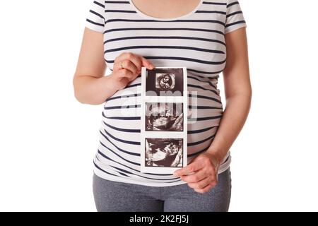 Eine Schwangerin steht und hält ihren Ultraschall-Baby-Scan Stockfoto