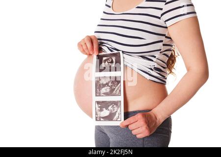 Eine Schwangerin steht und hält ihren Ultraschall-Baby-Scan Stockfoto