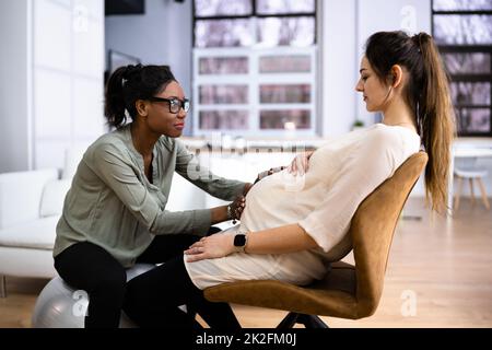 Schwangere bei einer Massage von einer afrikanischen Therapeutin Stockfoto