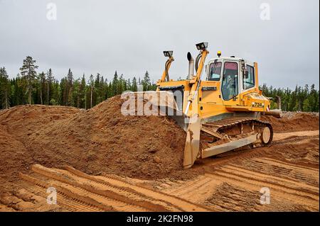 Ein gelber Traktor legt den Standort mit Sand ab Stockfoto