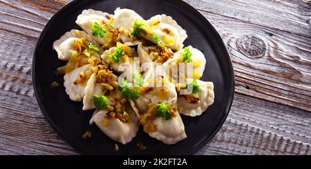 Komposition mit einem Teller klassischer Pierogien mit Zwiebeln Stockfoto