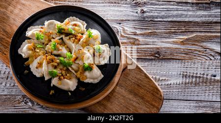 Komposition mit einem Teller klassischer Pierogien mit Zwiebeln Stockfoto