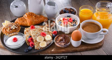 Frühstück mit Kaffee, Saft, Pfannkuchen und Croissants Stockfoto