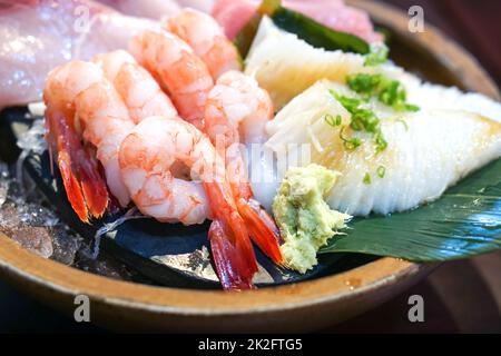 Das Sashimi-Set ist wunderschön in einem Holzteller angeordnet. Buffet Mit Japanischer Küche. Der Koch hat die Wahl: Garnelen, Engawa, Thunfisch und Hamachi Stockfoto