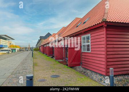 Einstöckige rote Holzhäuser mit Büros und Geschäften auf der Insel Christianshavn in der Nähe des Kopenhagener Opernhauses. Dänemark Stockfoto