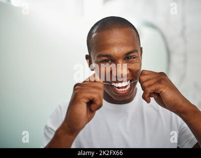 In diese Bereiche zu gelangen, in denen meine Zahnbürste nicht mehr in der Porträt eines hübschen jungen Mannes, der zu Hause im Badezimmer seine Zähne mit Zahnseide putzt. Stockfoto