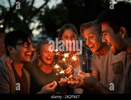 Es sind die einfachen Dinge im Leben, die wichtig sind. Aufnahme einer Gruppe von fröhlichen jungen Freunden, die sich nachts mit Wunderkerzen amüsieren. Stockfoto