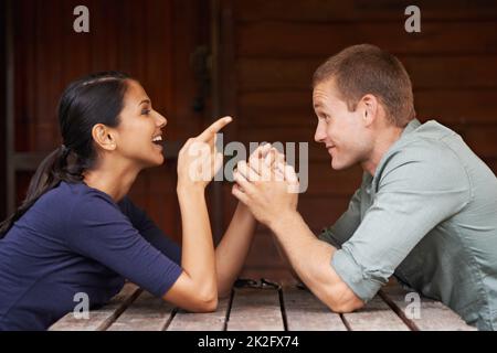Hahaa... Ihr sucht nach Ärger, Mister. Ein verspieltes Paar, das beim Date in einem Café lacht. Stockfoto
