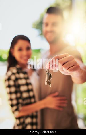 Wir besitzen sie jetzt. Porträt eines jungen Paares, das die Schlüssel zu ihrem neuen Zuhause hält. Stockfoto