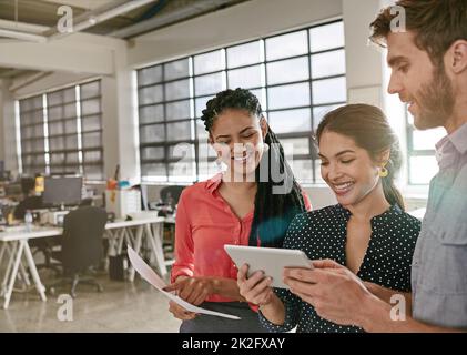 Dinge mit gemeinsamen Ideen umsetzen. Aufnahme einer Gruppe von Kollegen, die während einer Brainstorming-Sitzung in einem modernen Büro ein digitales Tablet verwendeten. Stockfoto