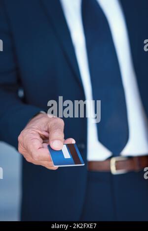 Legen Sie es auf das Geschäftskonto. Ausgeschnittene Aufnahme eines nicht erkennbaren Geschäftsmannes, der eine Kreditkarte hält. Stockfoto
