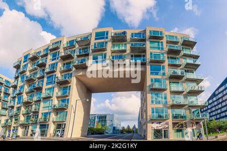 Ein modernes Bürogebäude und ein Wohnhaus mit einer Asphaltstraße für Autos, die durch einen Bogen in der Gegend von Ã˜restad fahren. Kopenhagen, Dänemark Stockfoto