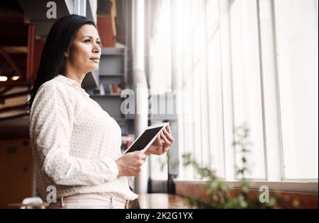 Ihre großen Träume sind auf dem Vormarsch. Aufnahme einer reifen Geschäftsfrau, die in einem Büro ein digitales Tablet benutzt. Stockfoto