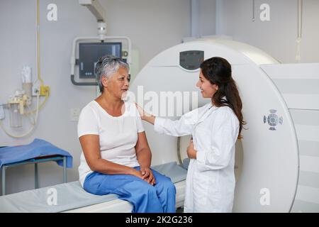 Dies ist ein völlig nichtinvasives Verfahren. Aufnahme einer älteren Frau, die zuvor von einem Arzt getröstet wurde, und einer MRT-Untersuchung. Stockfoto