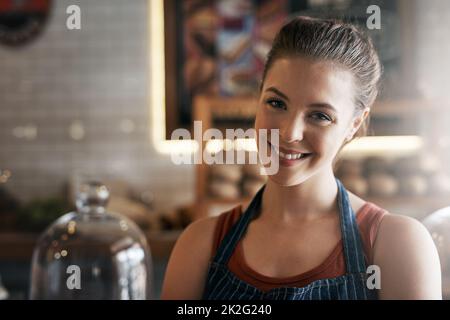 Für alle, die eine Kaffeepause brauchen. Porträt einer selbstbewussten jungen Frau, die in einem Café arbeitet. Stockfoto