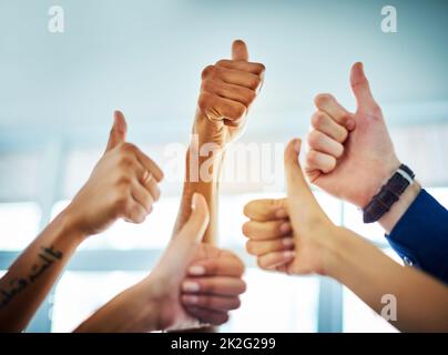 Ja, ja, es gibt kein Zurück. Eine kurze Aufnahme einer Gruppe von nicht erkennbaren Geschäftsleuten, die in einem modernen Büro den Daumen hoch zeigten. Stockfoto