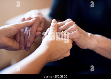 Ich bin für Sie da. Zugeschnittene Aufnahme einer Person, die eine ältere Frau in den Händen hält. Stockfoto