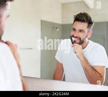 Sauberkeit ist neben Gottseligkeit. Die kurze Aufnahme eines hübschen jungen Mannes, der durchläuft, ist die morgendliche Routine im Badezimmer. Stockfoto