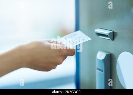 Zahlen Sie für die Sicherheit. Zugeschnittene Aufnahme einer nicht erkennbaren Person, die ein Ticket in einen Zähler einführt. Stockfoto