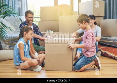 Ihre Familie wurde am Tag der Bewegung bedeckt. Aufnahme einer vierköpfigen Familie, die sich am Umzugstag gegenseitig beim Packen von Kartons unterstützt. Stockfoto