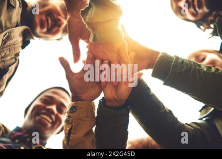 Einen Pakt schließen, um für immer Freunde zu bleiben. Aufnahme einer Gruppe von Freunden, die sich im Freien die Hände stapeln. Stockfoto