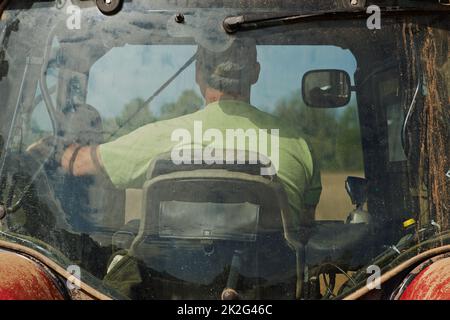 Diese Familie arbeitet hart. Aufnahme eines Jungen, der mit seinem Vater im Fahrerhaus eines modernen Traktors sitzt. Stockfoto