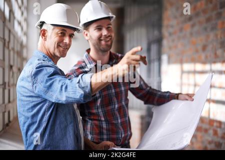 Fangen wir noch einmal an. Aufnahme von zwei männlichen Architekten, die Harthüte tragen und ein Gebäude inspizieren. Stockfoto