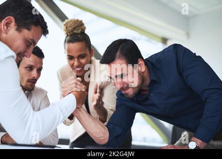 So leicht werde ich nicht aufgeben. Aufnahme von zwei Geschäftsleuten, die in einem Büro am Arm ringen. Stockfoto