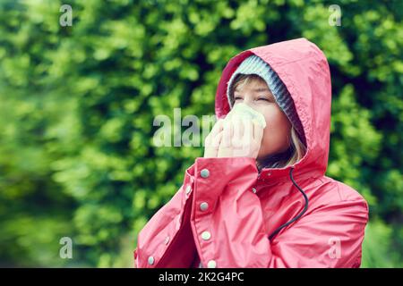 Die Jahreszeiten ändern sich, und meine Gesundheit ebenfalls. Kurzer Schuss einer jungen Frau, die ihre Nase im Freien bläst. Stockfoto