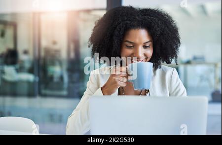 Es gibt nichts Besseres als eine Tasse Kaffee, um Sie in Gang zu halten. Aufnahme einer jungen Geschäftsfrau, die eine Tasse Kaffee trinkt, während sie an ihrem Schreibtisch arbeitet. Stockfoto