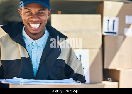 Wir können überall im Land liefern. Porträt eines Kuriers, der Kisten aus seinem Lieferwagen auslädt. Stockfoto