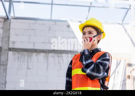 Asiatischer Ingenieur, Vorarbeiter, Architektin, Arbeiterin auf einer Baustelle, die mit Radio spricht Stockfoto