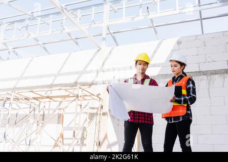 Architekt und Bauherr besprechen den Plan mit dem Bauplan des Gebäudes auf der Baustelle Stockfoto