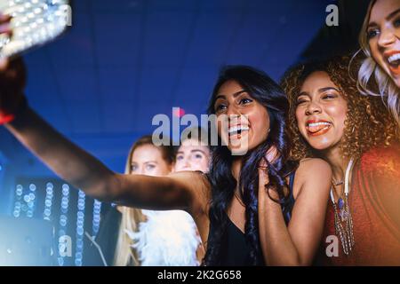 Es ist eine tolle Nacht, an die man sich erinnern sollte. Ausgeschnittene Aufnahme einer Gruppe von Freunden, die während einer Party in einem Club ein Selfie gemacht haben. Stockfoto