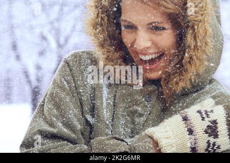 Den ersten Schneefall lieben. Aufnahme einer attraktiven Frau, die sich draußen im Schnee amügt. Stockfoto