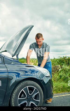 Mal sehen, was mit diesem Ding falsch ist. Aufnahme eines jungen Mannes, der unter der Motorhaube seines Autos nach dem Einbruch auf der Straße nachprüfte. Stockfoto