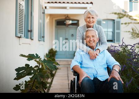 Unsere Liebe füreinander wird sich nie ändern. Porträt eines fröhlichen, im Rollstuhl gebundenen älteren Mannes, der sich mit seiner Frau zu Hause in ihrem Hinterhof entspannt. Stockfoto