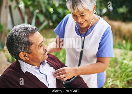 Sicherstellen, dass ihre Patienten gut versorgt werden. Ausgeschnittene Aufnahme eines älteren Mannes, der von einer Krankenschwester in einem Altersheim betreut wird. Stockfoto