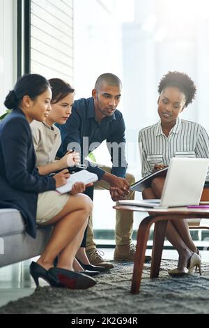 Ihre Ideen in den Fokus rücken. Aufnahme einer Gruppe von Geschäftsleuten, die während eines Meetings über einen Laptop miteinander sprechen. Stockfoto