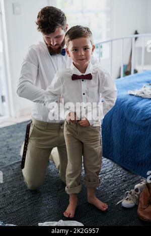Fast fertig und fertig. Aufnahme eines entzückenden kleinen Jungen und seines Vaters, der sich in passende Outfits kleidete. Stockfoto