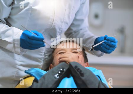 Ich habe Angst, den Mund zu öffnen. Aufnahme eines verängstigten kleinen Jungen, der auf einem Zahnarztstuhl liegt und seinen Mund geschlossen hält, damit der Zahnarzt nicht an ihm arbeitet. Stockfoto
