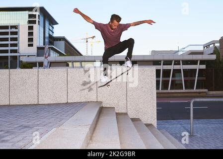 Im Skateboarding gibt es keine Grenzen. Aufnahme eines jungen Mannes, der eine Treppe hinuntergefahren ist. Stockfoto