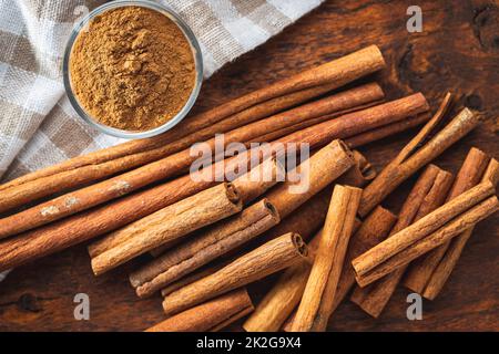 Trockene Zimtstäbchen und Zimtpulver auf Holztisch. Zimt-Gewürz. Stockfoto