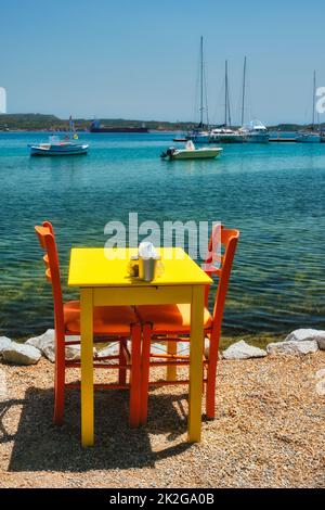 Café Tableon Strand in Adamantas Stadt auf Milos Insel mit Ägäis mit Booten im Hintergrund Stockfoto