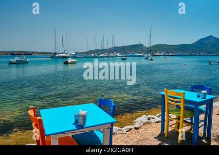 Café Tableon Strand in Adamantas Stadt auf Milos Insel mit Ägäis mit Booten im Hintergrund Stockfoto