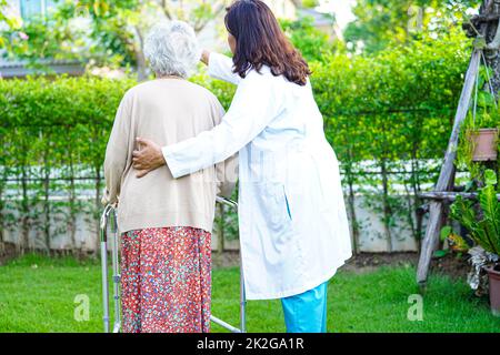 Arzt Hilfe Asian ältere Frau Behinderung Patient gehen mit Wanderer im Park, medizinisches Konzept. Stockfoto