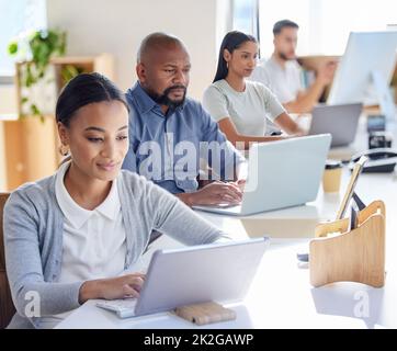 In diesem Büro können Sie ein hohes Maß an Produktivität spüren. Aufnahme einer Gruppe von Geschäftsleuten, die in einem Büro an Laptops arbeiten. Stockfoto