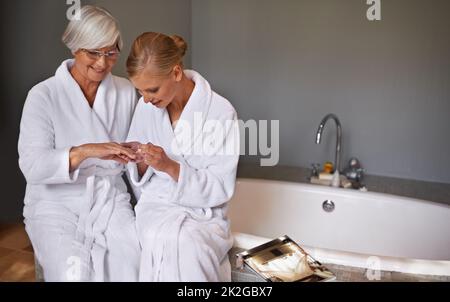 Sich gut um ihre Großmutter kümmern. Enkelin malt ihrer Großmutter Nägel. Stockfoto