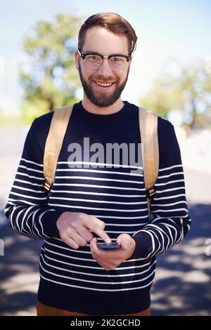 Der Inbegriff von Geek trifft auf Hip trifft auf den modernen Hipster. Ein hübscher junger Hipster im Freien, während er eine Brille trägt. Stockfoto